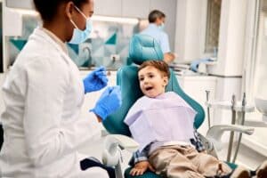 Young boy in dental chair smiling during examination with pediatric dentist in Melissa, TX.