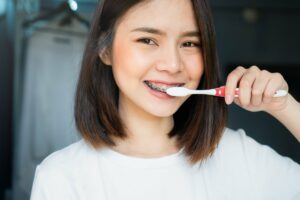 Young woman with braces brushing her teeth properly using correct technique.