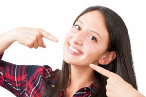 Woman demonstrating small size with fingers while smiling, illustrating dental benefits concepts.