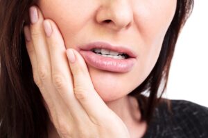 Woman holding cheek in pain, illustrating gum disease symptoms and discomfort.
