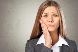 Woman with tooth pain holding her cheek, expressing discomfort from gum disease.