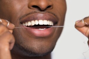 Man flossing teeth to demonstrate proper dental hygiene technique.