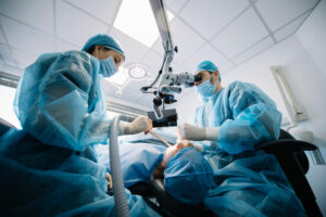 Oral surgeon and assistant performing dental surgery on patient in sterile operating room.