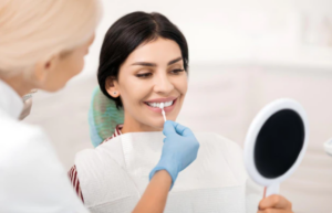 Dentist applying whitening treatment to patient's teeth during cosmetic dental procedure.