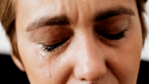 Close-up of woman with eyes closed showing tears, depicting emotional response to gum disease concerns.