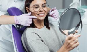 Dentist showing patient results in mirror after sedation dental treatment in Melissa.