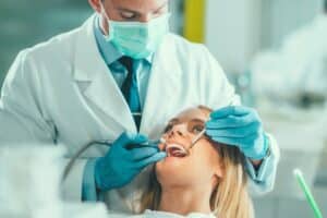 Dentist examining patient's teeth during routine dental care appointment.