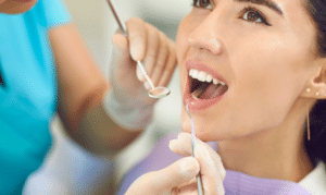 Patient receiving dental examination with mirror and explorer tools during checkup.
