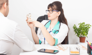 Female dentist examining dental model with patient in Melissa, TX office.