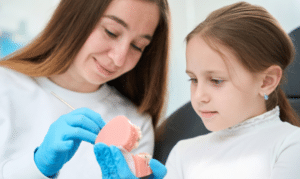 Pediatric dentist showing young patient a dental model during consultation in Melissa, TX.