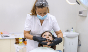 Dental hygienist examining patient's mouth during oral examination in Melissa dental office.