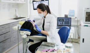 Dentist examining patient's teeth during first dental visit in modern dental office.