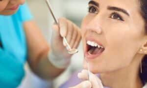 Patient receiving dental examination from dentist during oral checkup procedure.
