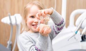 Happy young child rinsing mouth with water during dental visit at pediatric dentistry office.