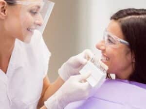 Dentist showing patient a dental crown shade guide during consultation in Melissa, TX.