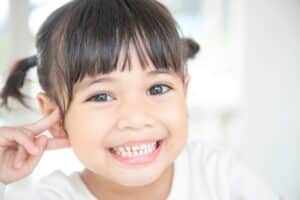 Smiling young girl with healthy teeth showing confidence in dental care.