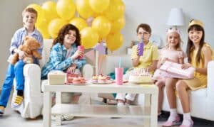 Happy children celebrating at a birthday party with yellow balloons and treats.