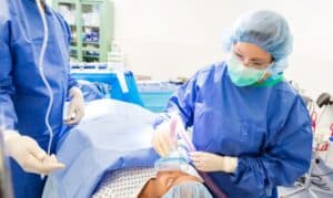 Dentist performing sedation dentistry procedure on patient in clinical setting.