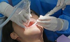 Dentist examining patient's mouth during root canal treatment with dental tools and suction device.