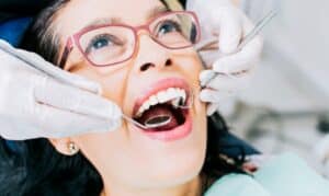 Young patient receiving dental examination with mirror and explorer tools during treatment.