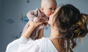 Mother holding her baby while smiling brightly, celebrating oral health and family care.