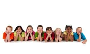 Group of smiling children in colorful shirts demonstrating healthy, happy smiles and oral wellness.