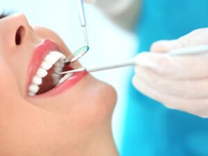 Dentist examining patient's teeth during dental examination with mirror and explorer tools.
