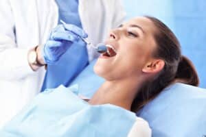 Dentist examining patient's teeth during dental checkup in treatment room.