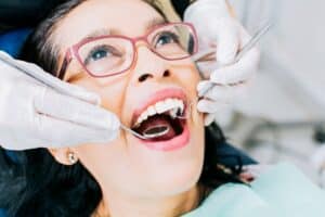 Patient receiving dental examination with mirror and explorer during professional checkup.