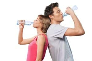 Young couple drinking water together during fitness routine to support oral health.