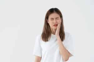 Woman with tooth pain holding her cheek, illustrating nighttime dental discomfort.