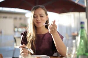 Woman eating outdoors demonstrating how food colors can stain teeth.