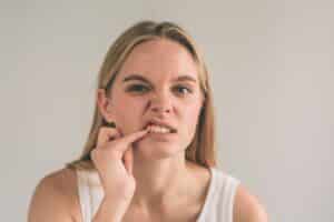 Woman with gum disease concerns pointing to her teeth during dental consultation.