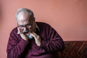 Senior man experiencing tooth pain, illustrating dental concerns addressed by cosmetic and restorative dentistry services.