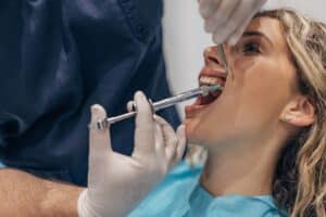 Dentist injecting local anesthetic into patient's gums during dental treatment in Melissa, TX.