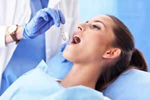 Dentist examining patient's teeth during root canal procedure in dental office.