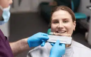 Dentist showing patient shade guide for dental veneer color matching during consultation.