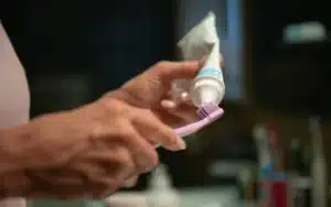 Parent holding toothbrush with fluoride toothpaste for child's dental care.