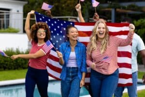 Young women celebrating Fourth of July with American flags and patriotic spirit.