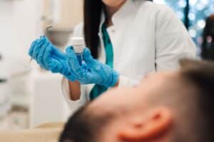 Dentist holding dental filling material in blue gloves during patient treatment.