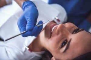 Dentist in blue gloves examining patient's teeth during professional cleaning appointment.