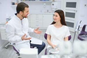 Dentist consulting with patient in modern dental office about holistic health factors.