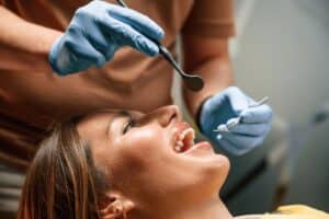 Dentist performing a tooth procedure on patient with blue gloves and dental tools.