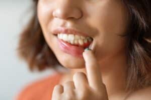 Woman pointing to inflamed gum tissue showing signs of gum disease and bleeding.